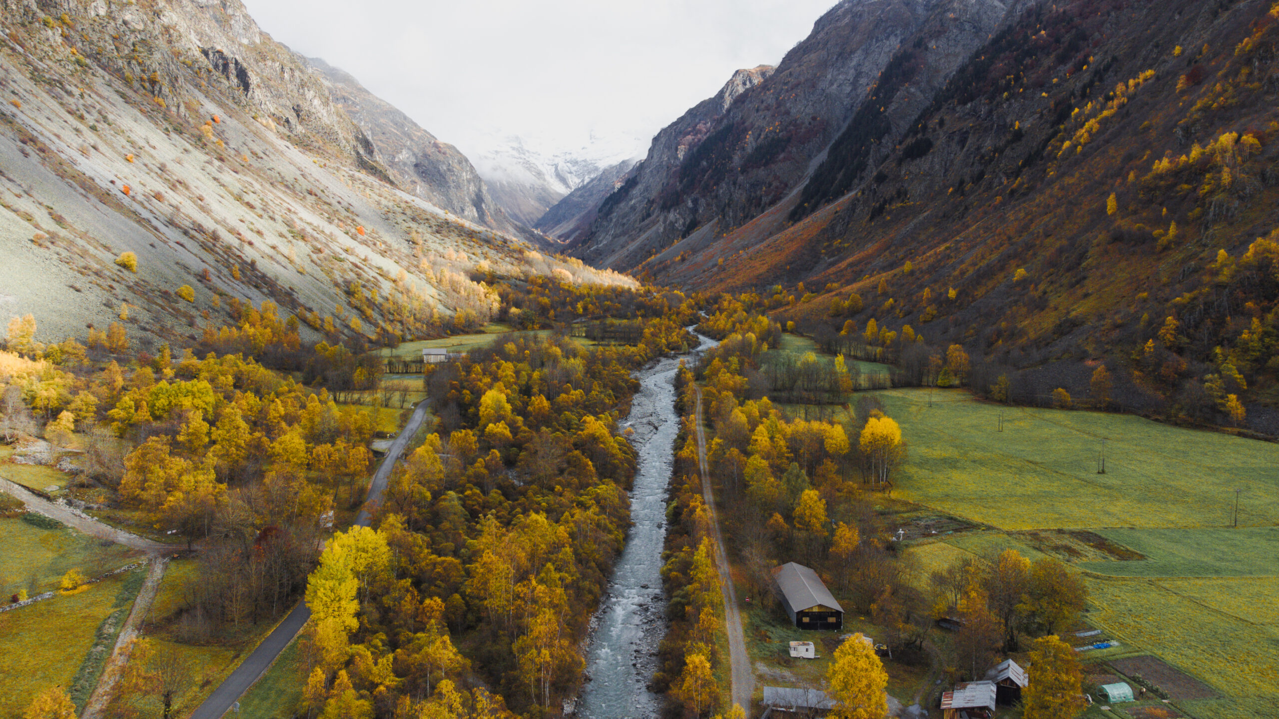 Luftaufnahme vom Nationalpark Ecrins in Frankreich. Fluss umgeben von Bäumen und Bergen in Herbst